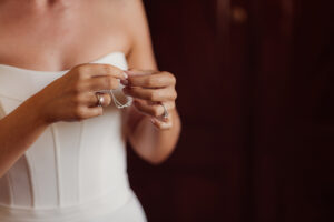 Bride in white undoing a bracelet